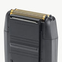 Close-up of a black electric shaver showing the top shaving head with a gold-toned mesh filter and silver blade edge, set against a plain light gray background.